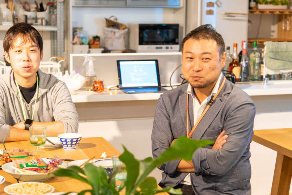 スナックビィーゴに参加した男性2人。食べ物を食べながら笑っている。